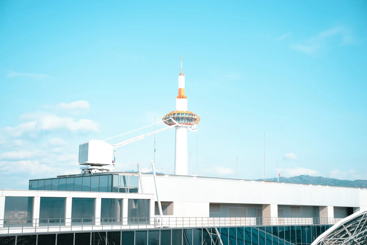 明るい空の下で、白い建物と塔を屋上越しに写した写真
