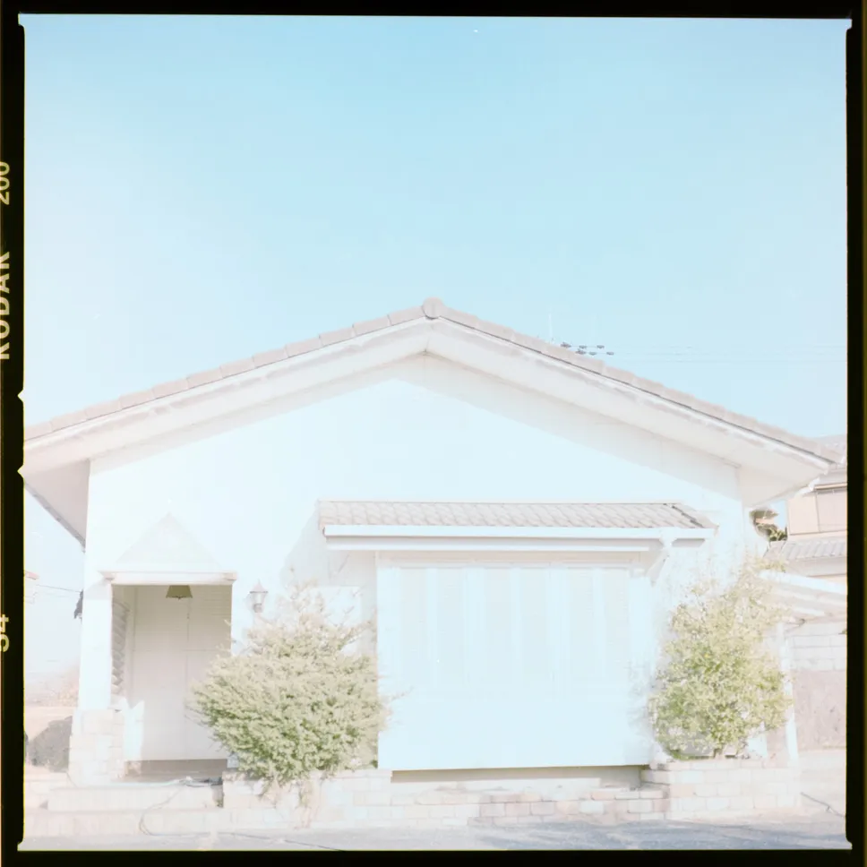 強い光を受けた白い建物の外壁と屋根を正面から写した写真