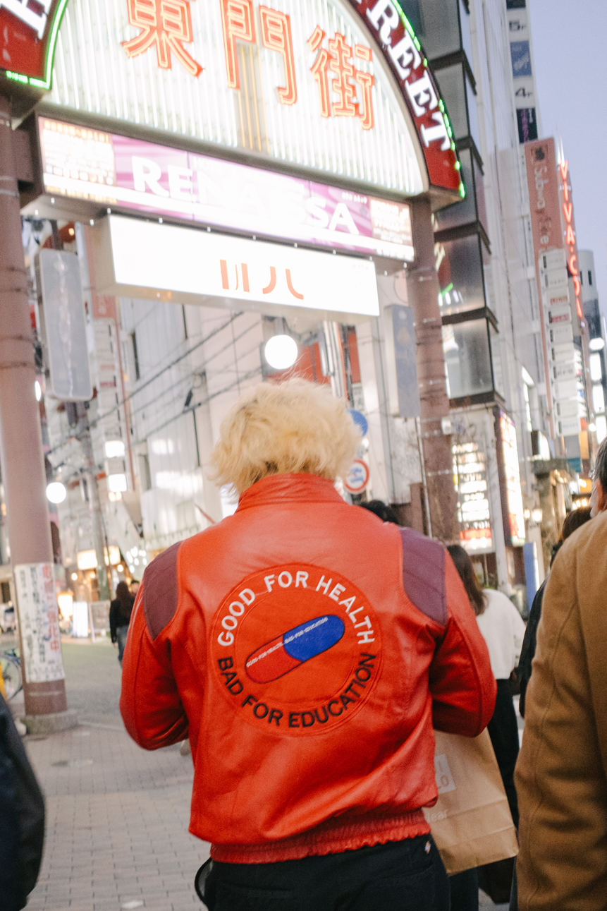 夜の繁華街で、赤い上着を着た人物の後ろ姿を写した写真