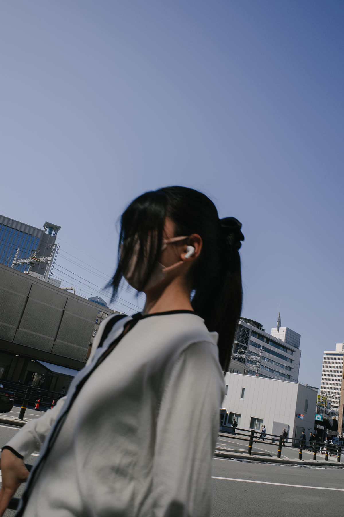 青空を背景に、白い服の人物が横を向いて立つ写真